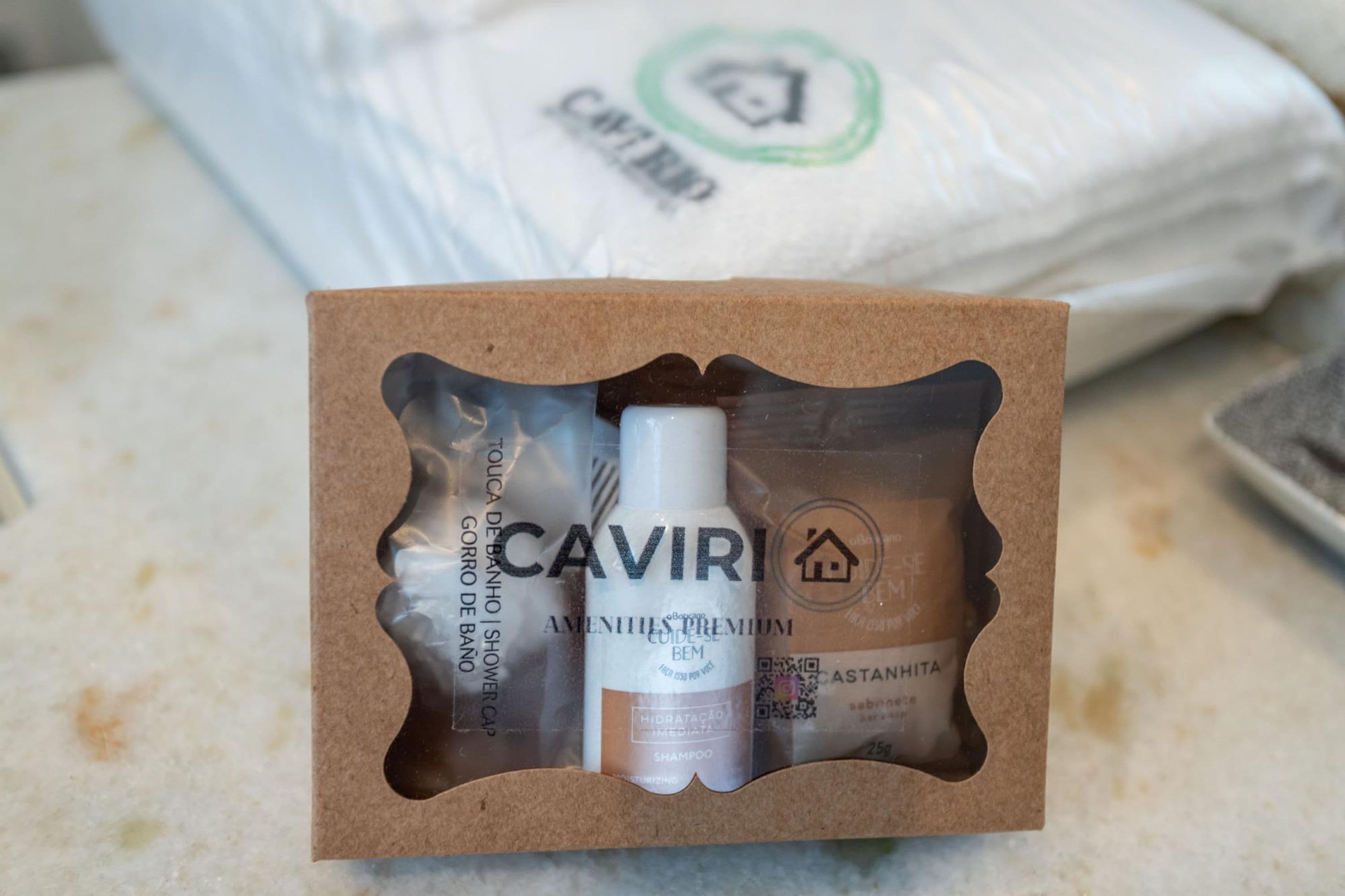 Une boîte en carton contenant un bonnet de douche, un flacon de shampoing et un flacon de gel douche.