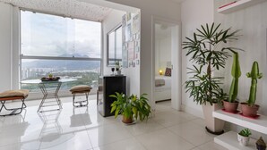 A modern living room with a large window, a dining area, and a variety of potted plants. - Coverage in Barra da Tijuca for 6 People Lc2207 (Rio de Janeiro)