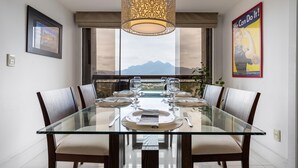 A dining area with a glass table, six chairs, and a decorative hanging light fixture. - Coverage in Barra da Tijuca for 6 People Lc2207 (Rio de Janeiro)