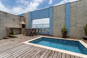 Enjoy breathtaking views of the city and mountains from this rooftop terrace, featuring a pool, deck, and comfortable seating area.