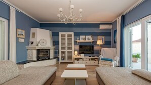 A living room with a fireplace, sofa, TV, and a chandelier. - Villa Tatijana Zadarvillas (Kukljica)