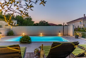 Ein Poolbereich mit Liegestühlen, einem Tisch mit Getränken und Blick auf den Pool.