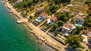 An aerial view of a coastal residential area with houses, a beach, and a bridge in the background. - Villa Tatijana Zadarvillas (Kukljica)