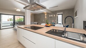 Een moderne keuken met een centraal eiland, een RVS-spoelbak en een ingebouwde oven.