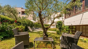 Ein Innenhof mit Korbmöbeln, einem kleinen Tisch und einem Baum.