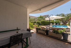 A covered patio with a table and chairs, a pool, and potted plants. - Villa Petra Zadarvillas (Bibinje)