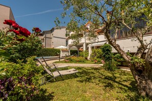 A courtyard with a pool, lounge chairs, and a garden with various plants and flowers. - Villa Petra Zadarvillas (Bibinje)