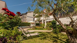 Ein Innenhof mit Pool, Liegestühlen und einem Garten mit verschiedenen Pflanzen und Blumen.