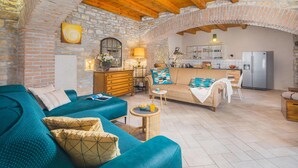 A cozy living room with a blue sofa, a wooden cabinet, and a kitchen area with a refrigerator and a dining table.