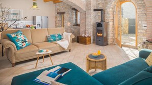 A cozy living room with a stone fireplace, a sofa, a coffee table, and a wicker side table.