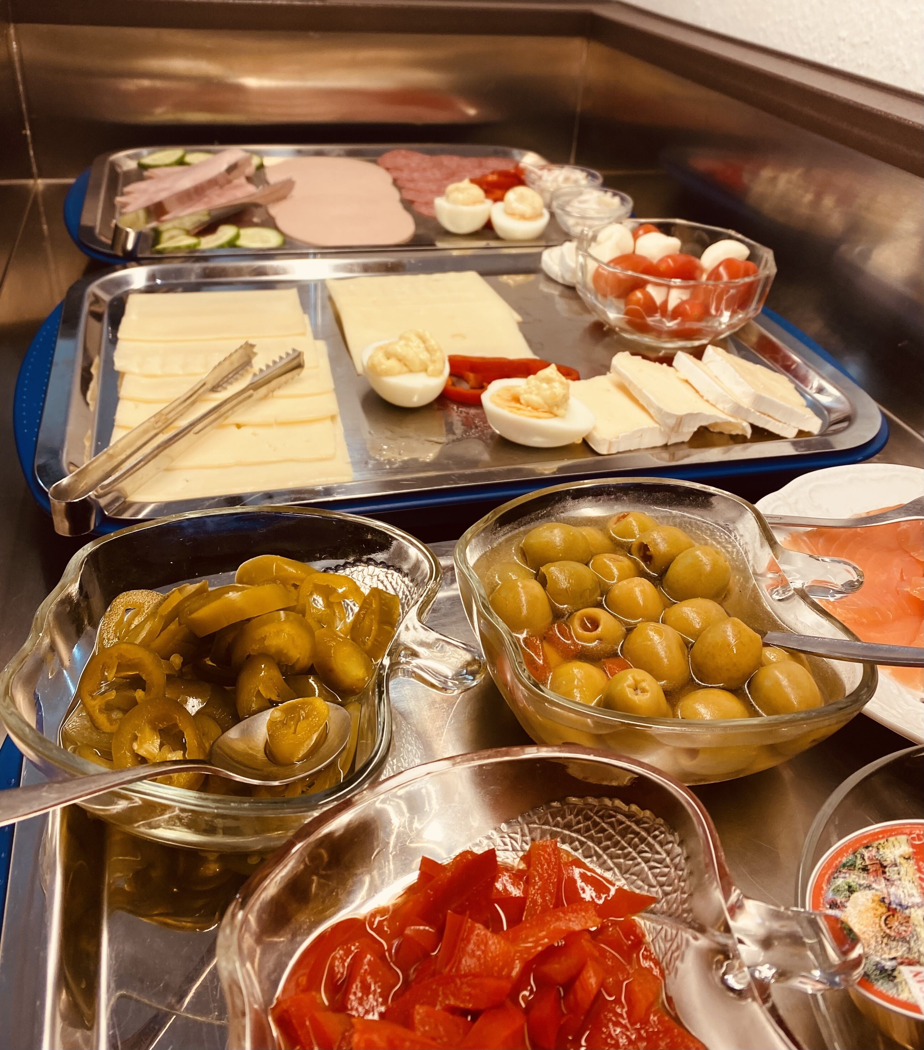 Een buffet met diverse soorten eten, zoals vleesschotels, kazen, eieren, olijven en ingelegde groenten.