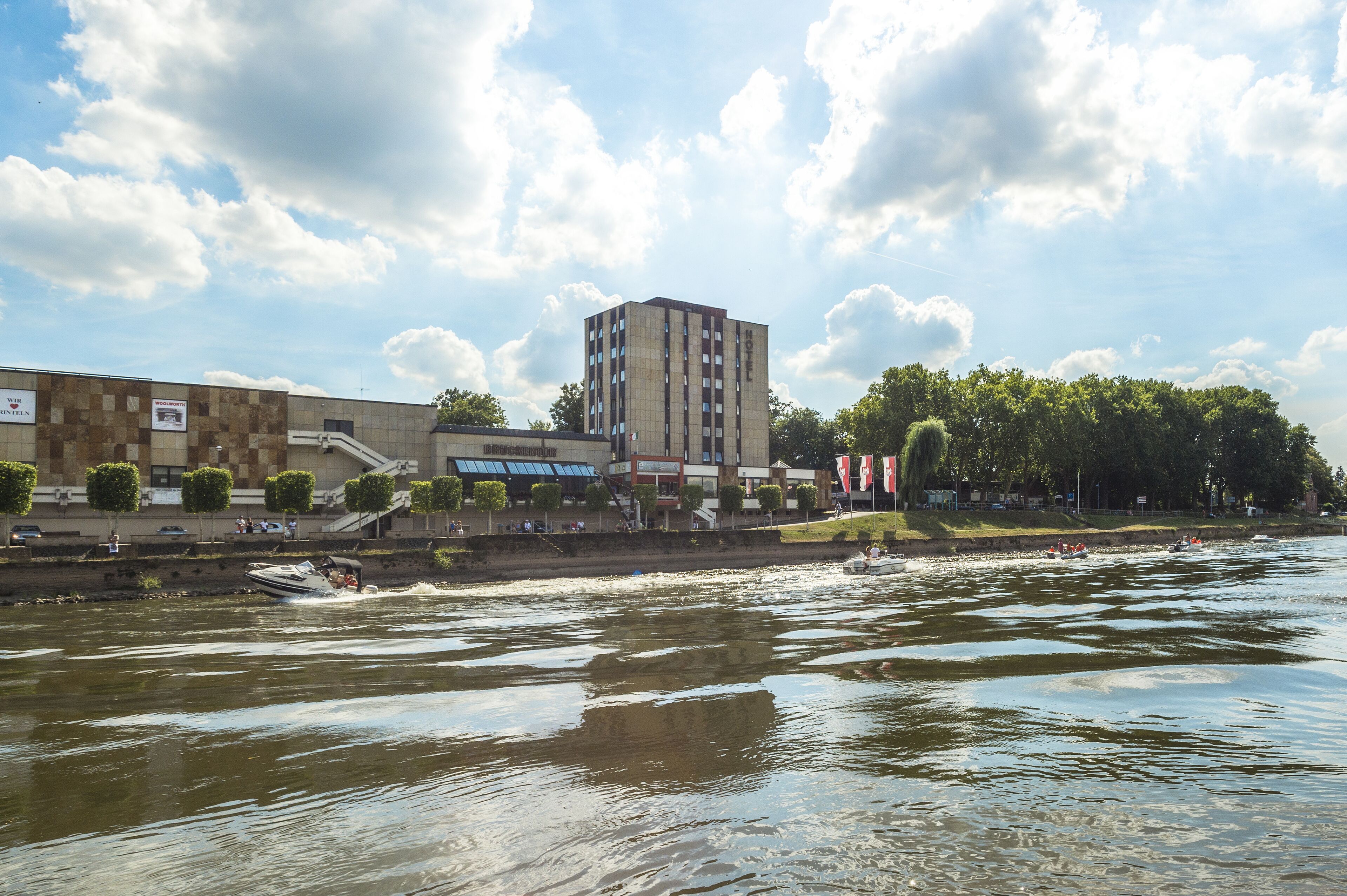A hotel with a modern design, located near a river with boats.