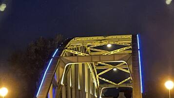 Ein Nachtblick auf eine Brücke mit beleuchteten Stahlträgern und einer Straße, die darüber führt.