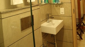 A bathroom with a sink, mirror, towel rack, and shelves with toiletries. - Hotel Reva Regency (Bhopal)