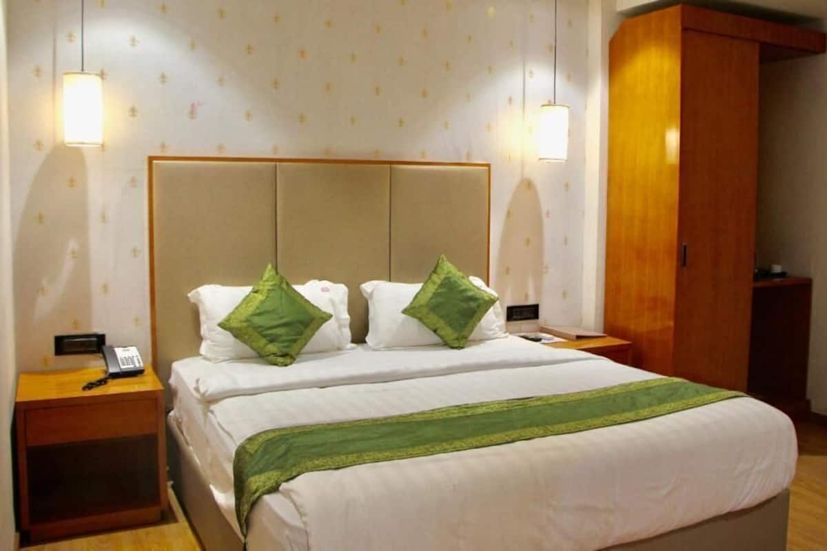 Quarto de hotel com uma cama, duas mesas de cabeceira, um guarda-roupa e um telefone fixo na parede.