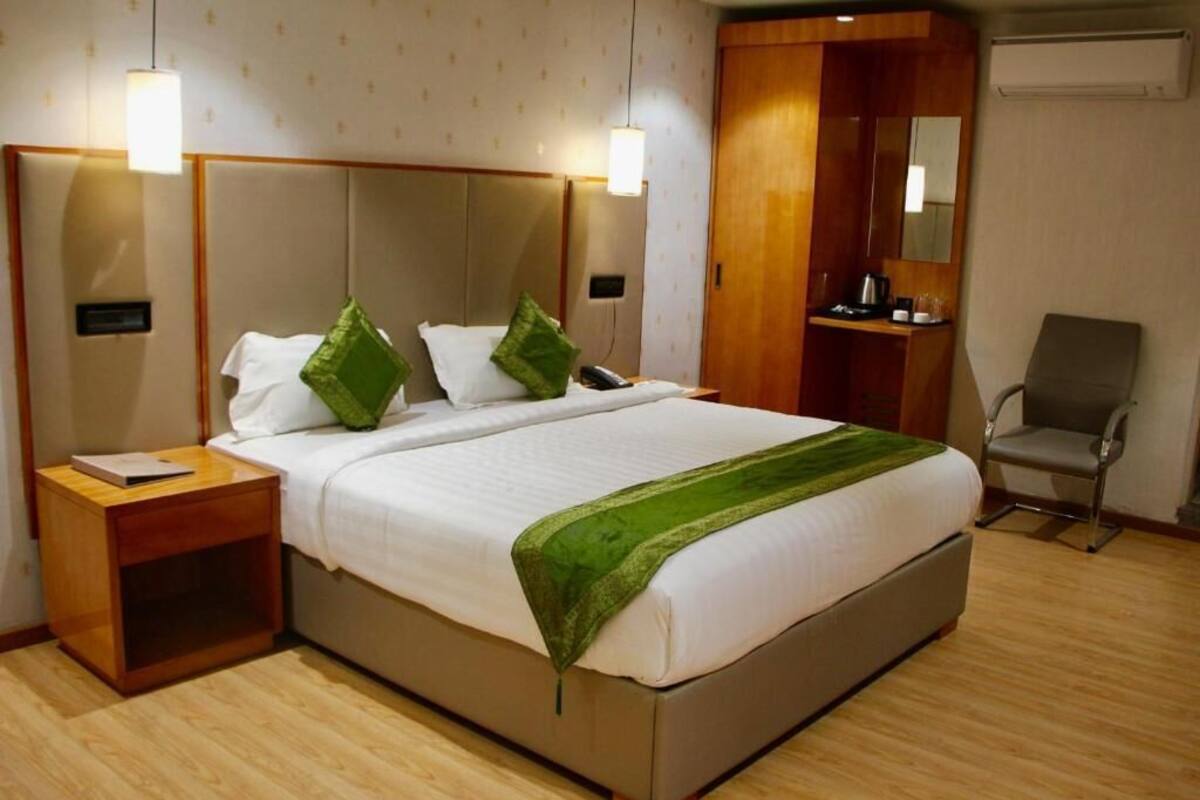 Quarto de hotel com uma cama, mesas de cabeceira, uma cadeira, guarda-roupa e um espelho.