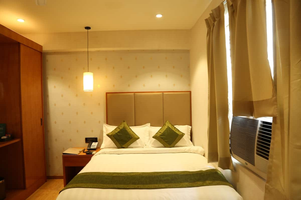 Quarto de hotel com cama, mesa de cabeceira, telefone e ar condicionado.