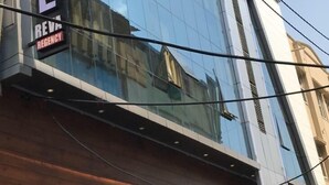 A modern hotel with a large glass facade reflecting the sky and nearby buildings. - Hotel Reva Regency (Bhopal)