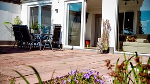 An outdoor patio with a table and chairs, a potted plant, and a view of the interior through glass doors. - "Pure relaxation: your exceptional vacation apartment in Winterberg!" (Winterberg)