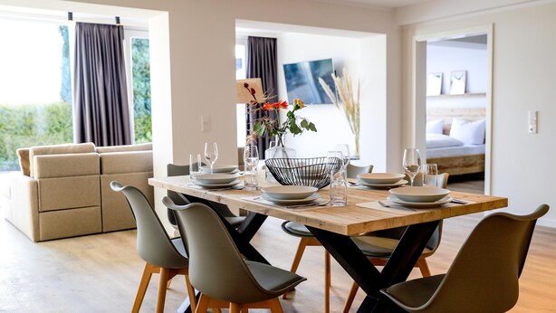 A modern dining area with a wooden table set for four, surrounded by contemporary chairs. - "Pure relaxation: your exceptional vacation apartment in Winterberg!" (Winterberg)