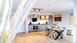 A modern kitchen with grey cabinets, a built-in oven, and a dining area with a wooden table and grey chairs. - "Pure relaxation: your exceptional vacation apartment in Winterberg!" (Winterberg)