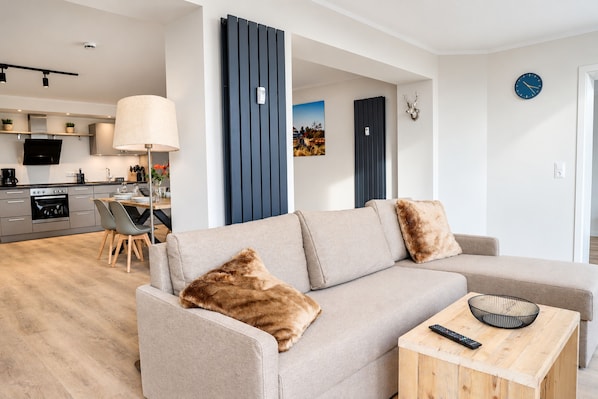 A modern living room with a sofa, a coffee table, and a remote control.