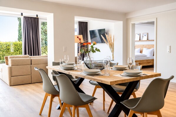 A modern dining area with a wooden table, grey chairs, and a vase with flowers.