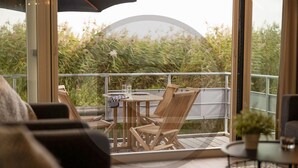 A balcony with wooden furniture, a round table, and a glass of water. - Stunning ship in Aalsmeer with kitchen (Aalsmeer)