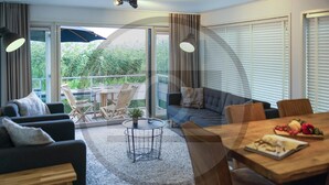 A modern living room with a sofa, chairs, a dining table, and a balcony with a view of greenery. - Stunning ship in Aalsmeer with kitchen (Aalsmeer)
