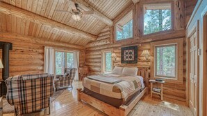 A log cabin bedroom with a wooden bed, a plaid sofa, and a ceiling fan. - Inviting and Relaxing-Cliffs and Streams! (Nathrop)
