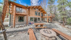 A log cabin with a stone foundation, multiple windows, and a fire pit area. - Inviting and Relaxing-Cliffs and Streams! (Nathrop)