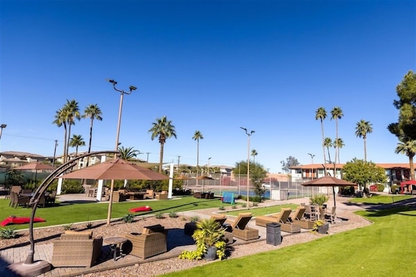 A resort with outdoor seating, palm trees, and a clear sky.