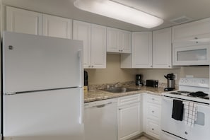 Fully equipped kitchen with refrigerator, microwave, stove, and sink.
