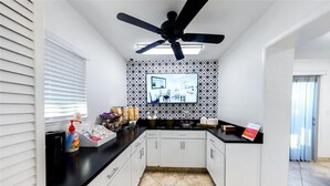 A modern kitchen with white cabinets, a black countertop, and a ceiling fan.