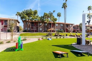 A courtyard with artificial grass, outdoor seating, and a pool area.