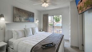 A hotel room with a bed, a ceiling fan, a painting, a TV, and a view of the outdoors. - 108 Fully Furnished 1BR Suite-Prime Location! by RedAwning (Scottsdale)