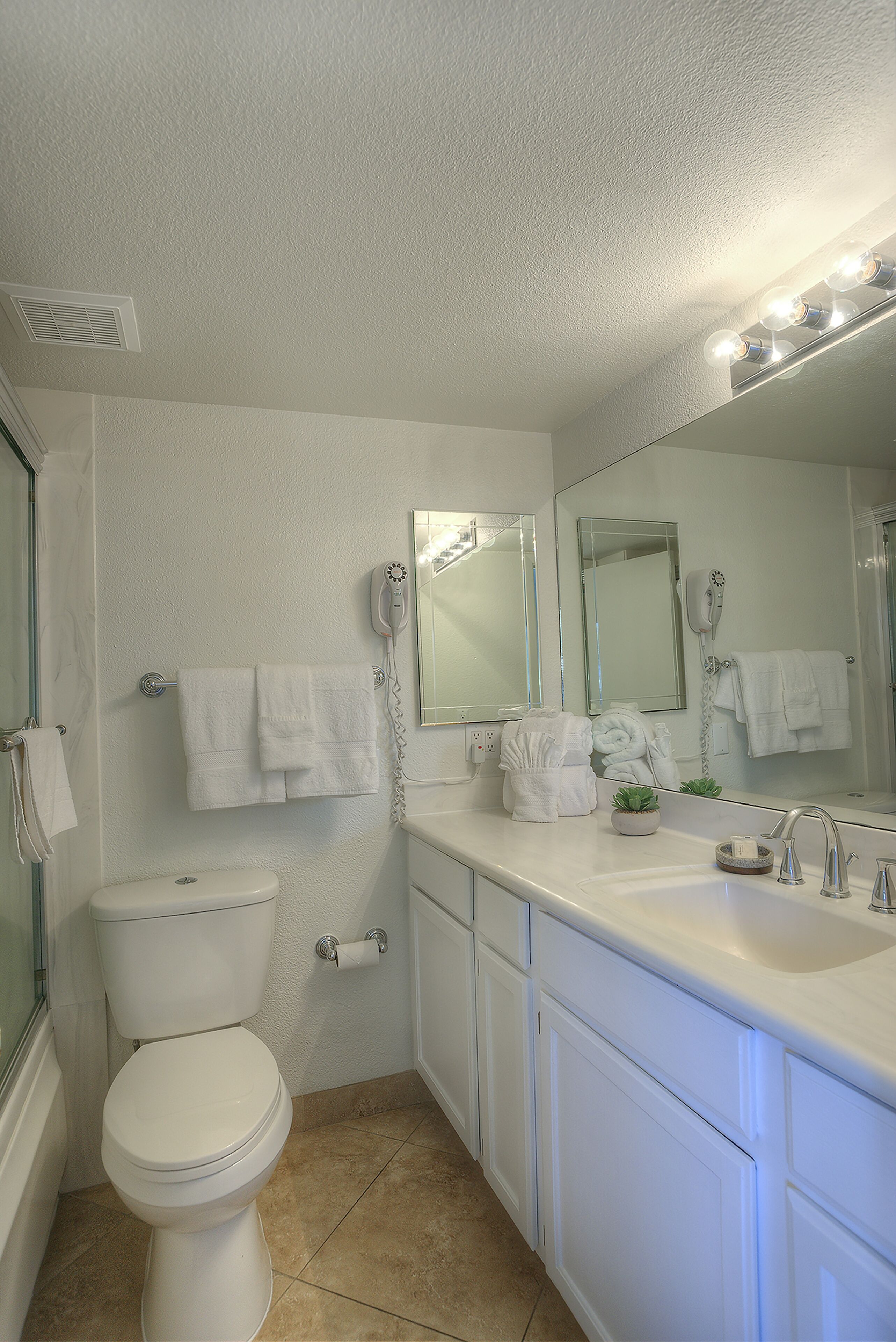 A bathroom with a toilet, sink, and mirrors.