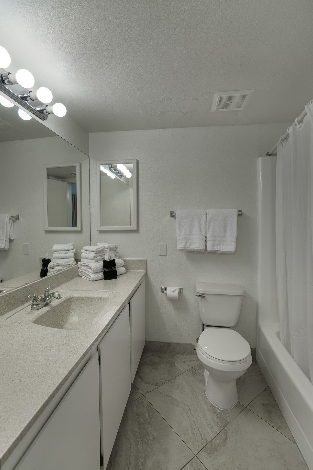 A bathroom with a sink, mirror, and toilet. There are towels and a bag on the counter.