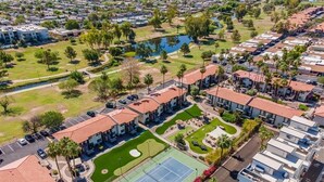 A residential area with multiple two-story buildings, a tennis court, and a small lake.