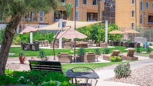 Un espace extérieur aménagé en terrasse, avec des meubles en osier, des parasols et une pelouse bien entretenue.