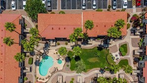 An aerial view of a residential area with a swimming pool, palm trees, and a parking lot. - 109 Fully Furnished 1BR Suite-Prime Location! by RedAwning (Scottsdale)