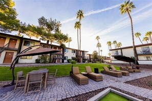 A courtyard with outdoor seating, palm trees, and a building with a modern design. - 142 Fully Furnished 1BR Suite-Pet Friendly! by RedAwning (Scottsdale)