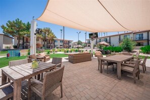 Un patio al aire libre con muebles de madera, un paraguas grande y un pequeño jardín.