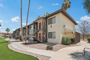 A multi-story building with a staircase, outdoor seating, and palm trees.