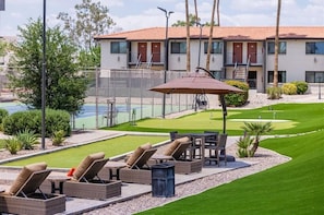 A poolside area with lounge chairs, a table, and a patio umbrella.