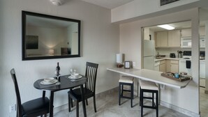 A compact kitchen with a microwave, stove, and a small dining area with a table and chairs.