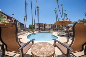 Relax by the resort's central pool, surrounded by lounge chairs and tables.