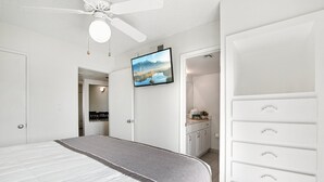 A bedroom with a bed, a ceiling fan, a TV, a dresser, and a closet. - 128 Fully Furnished 1BR Suite-Prime Location! by RedAwning (Scottsdale)