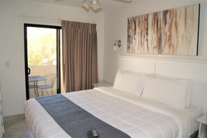 Relax in this serene space with a large bed, a sliding door to an outdoor area, and a wall-mounted light fixture.
