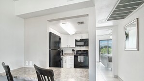 A modern kitchen with white cabinets, a black refrigerator, a microwave, and a stove. There is a dining area with a table and chairs. - 128 Fully Furnished 1BR Suite-Prime Location! by RedAwning (Scottsdale)
